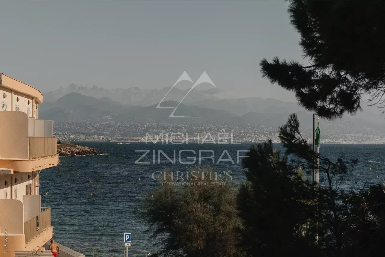Vue sur la mer depuis le Cap d'Antibes, avec des montagnes en arrière-plan.