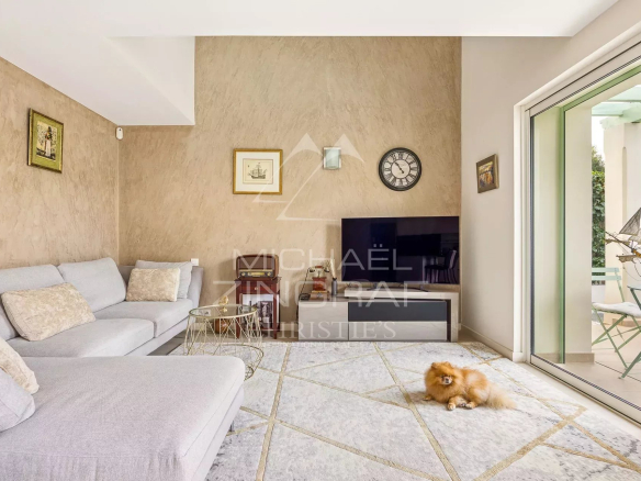 Intérieur d'une maison rénovée avec un salon lumineux et un petit chien sur le tapis.