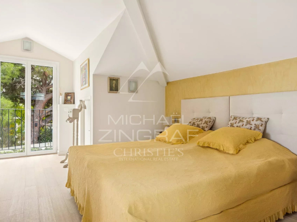 Chambre d'une maison rénovée au Cap d'Antibes, avec un lit double et des fenêtres donnant sur l'extérieur.