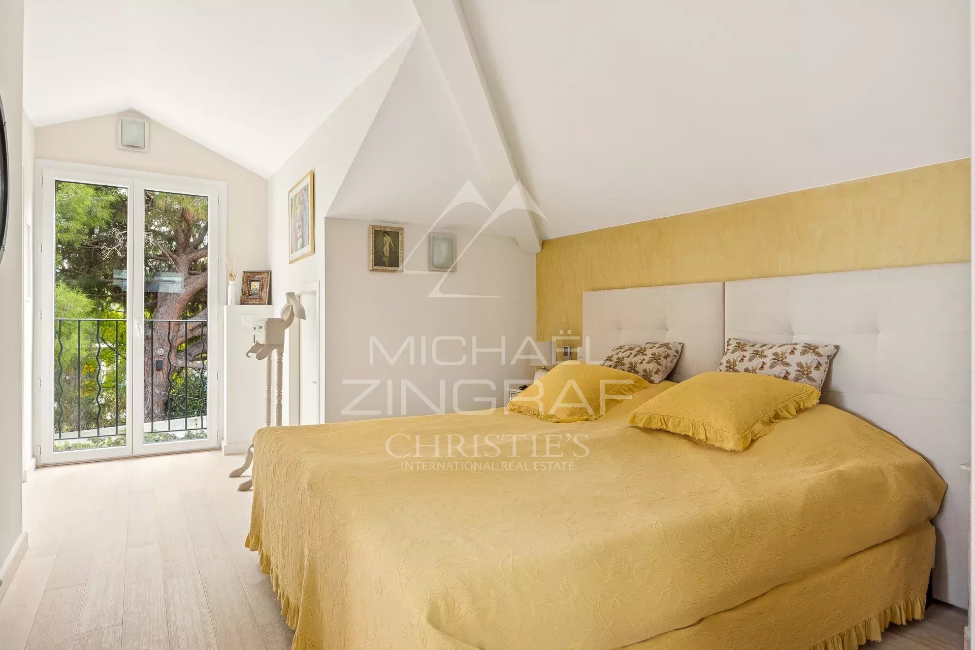 Chambre d'une maison rénovée au Cap d'Antibes, avec un lit double et des fenêtres donnant sur l'extérieur.
