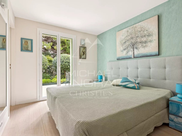 Chambre d'une maison rénovée au Cap d'Antibes, avec lit double et accès à un jardin.