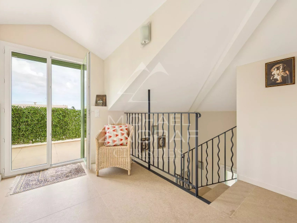 Intérieur d'une maison rénovée au Cap d'Antibes avec un escalier et une vue sur l'extérieur.