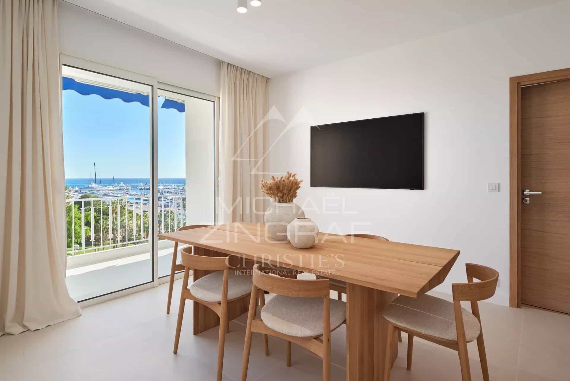 Intérieur d'un appartement à Cannes avec vue sur la mer, salle à manger moderne et balcon.