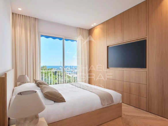 Chambre d'un appartement rénové à Cannes avec vue mer, mobilier moderne et lumineux.