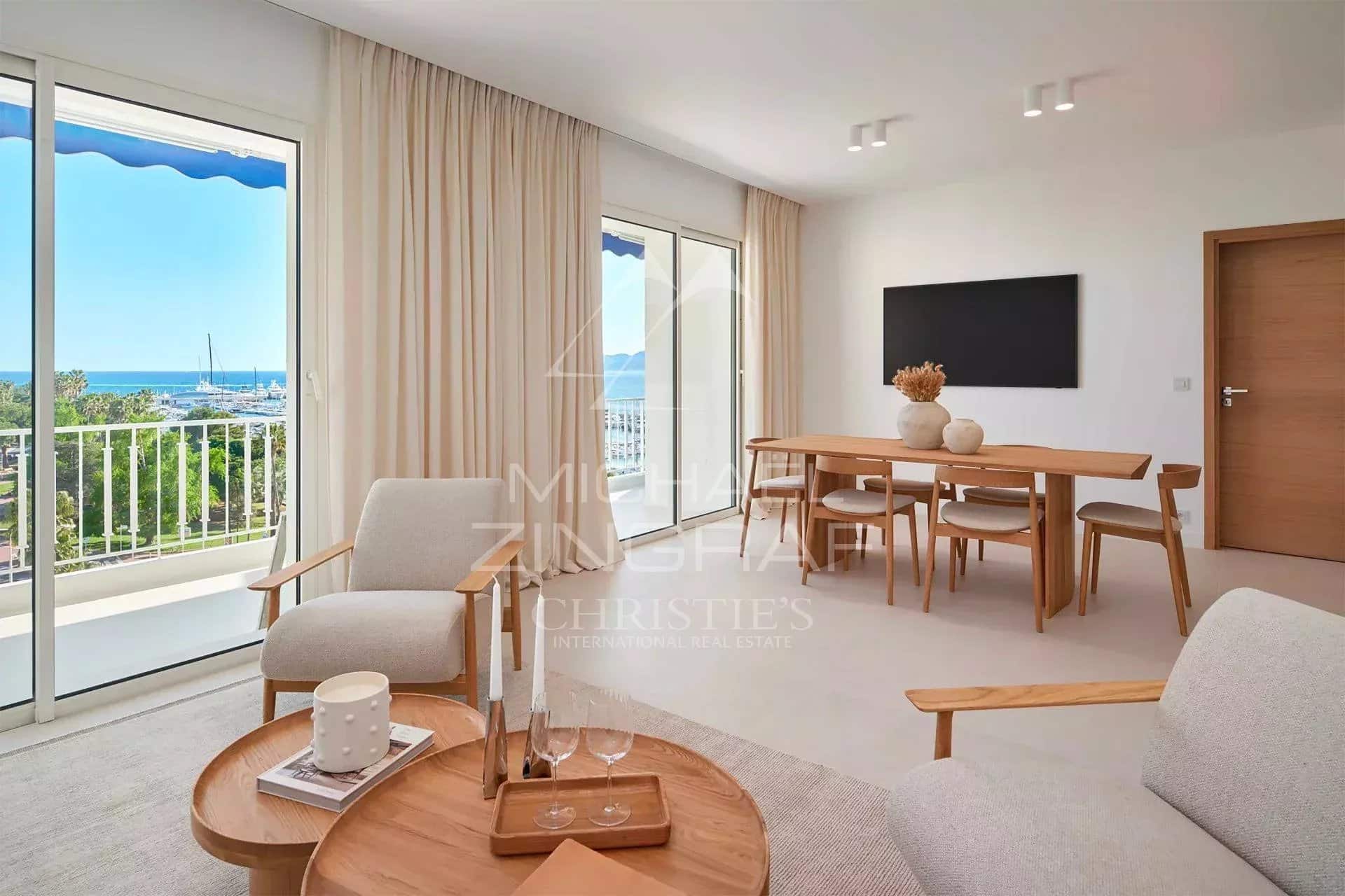 Intérieur d'un appartement rénové à Cannes avec vue sur la mer, comprenant un salon et une salle à manger.