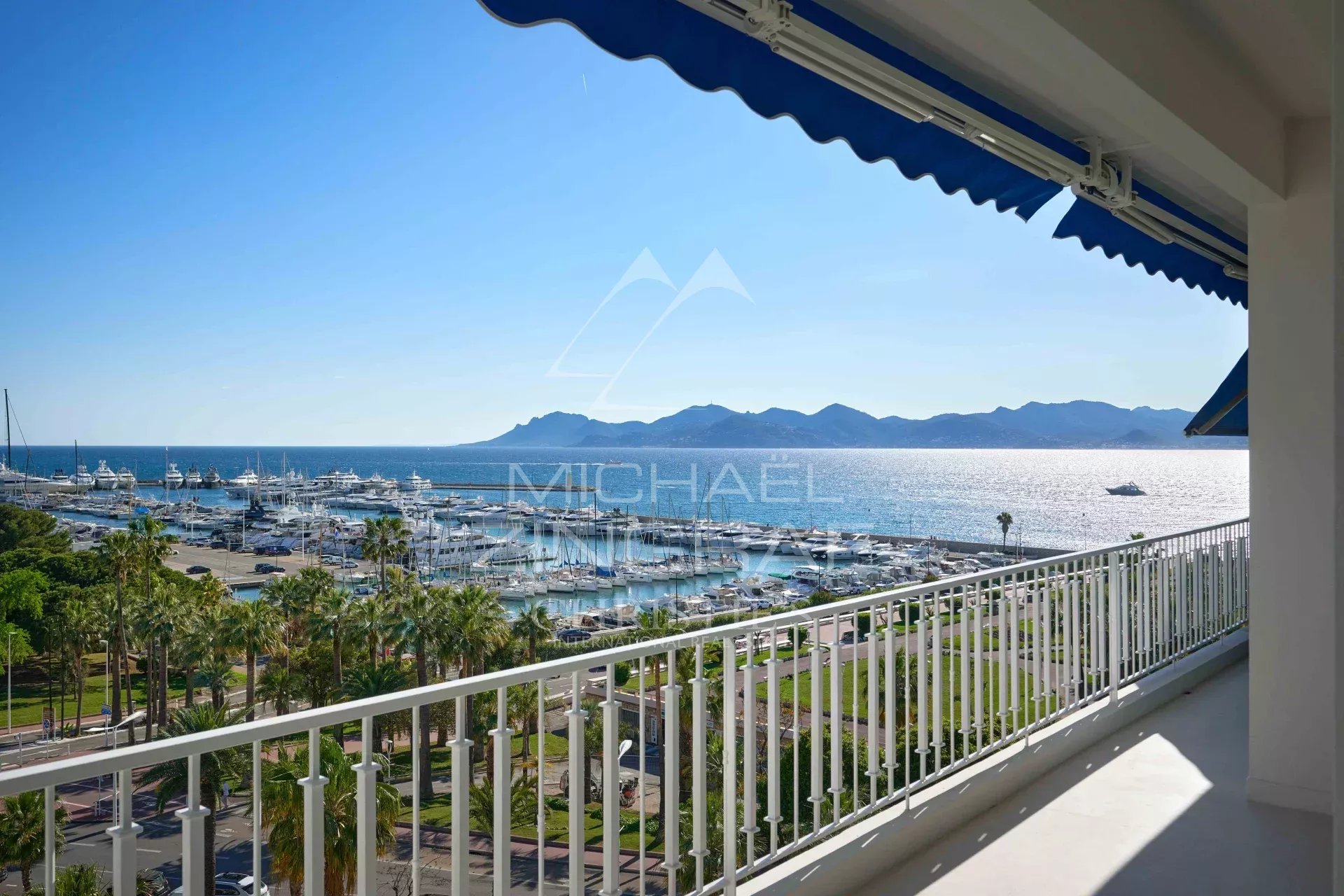 Vue mer depuis un balcon d'un appartement à Cannes, avec le Port Canto et les montagnes en arrière-plan.