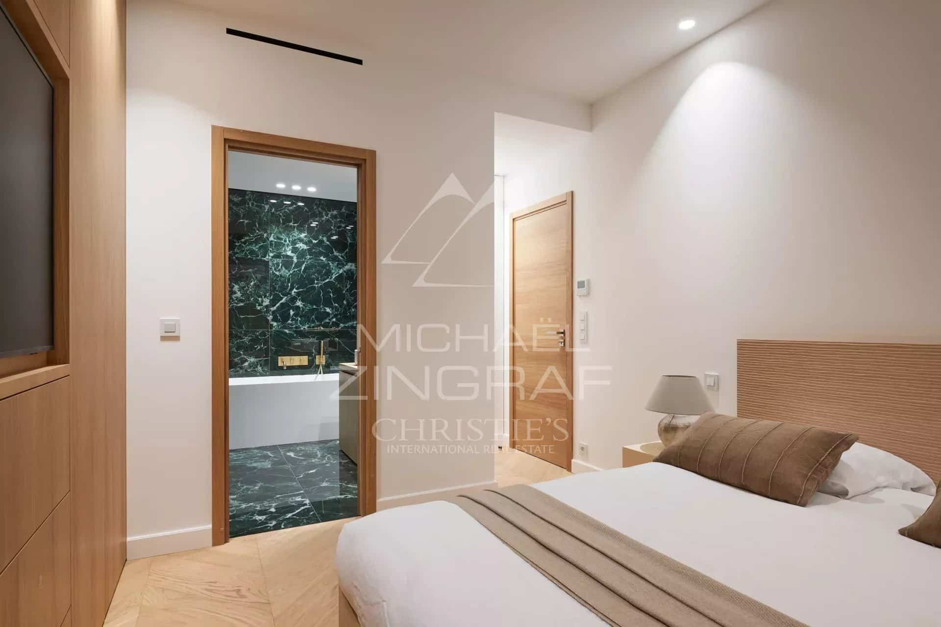 Chambre d'un appartement rénové avec salle de bain, murs clairs et décoration moderne.