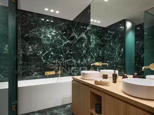 Salle de bain moderne avec baignoire et vasques, décorée de marbre vert et bois.