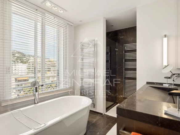 Modern bathroom with bathtub and shower, windows with wooden shutters.