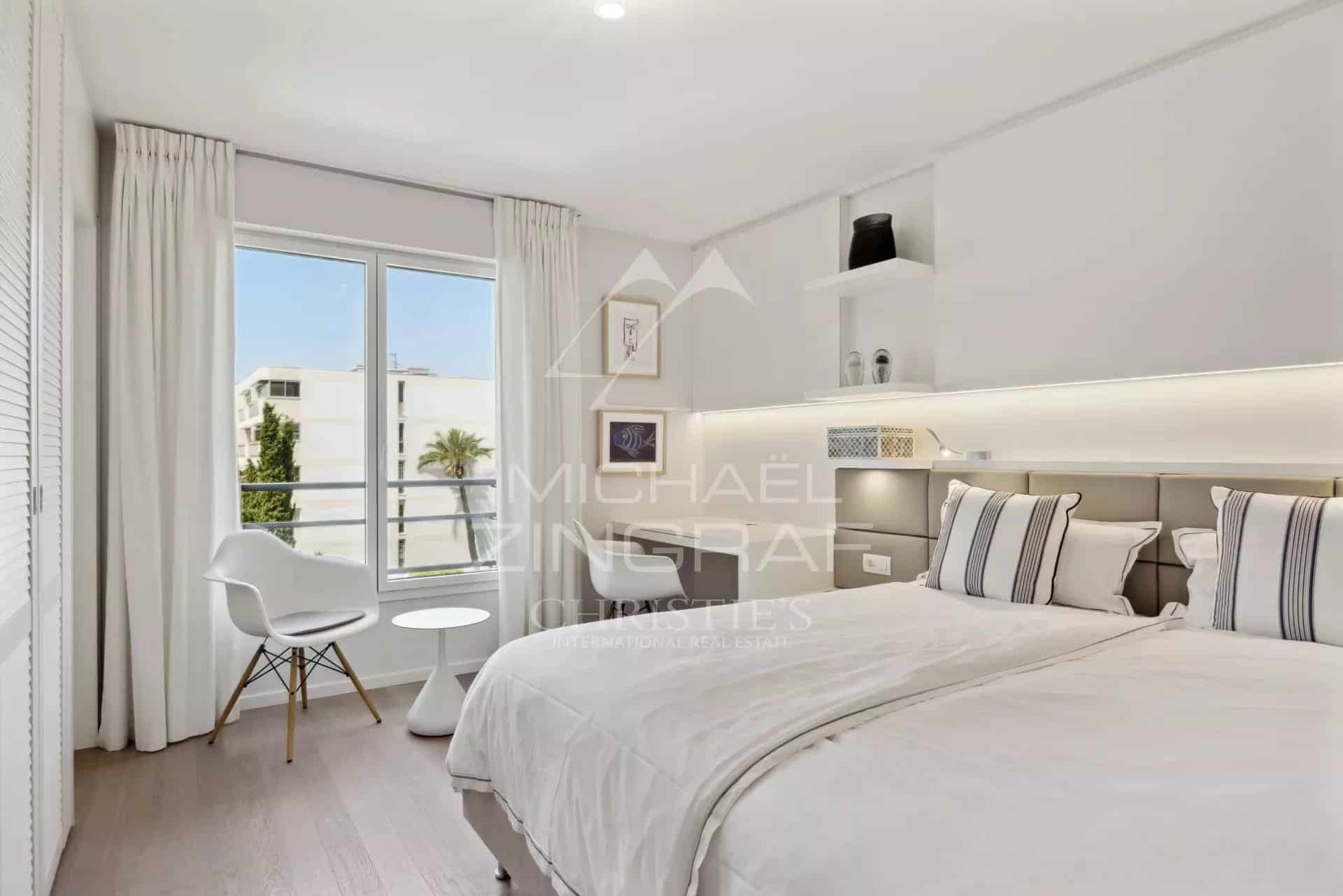Chambre d'un appartement à Cannes avec lits jumeaux et vue sur l'extérieur.