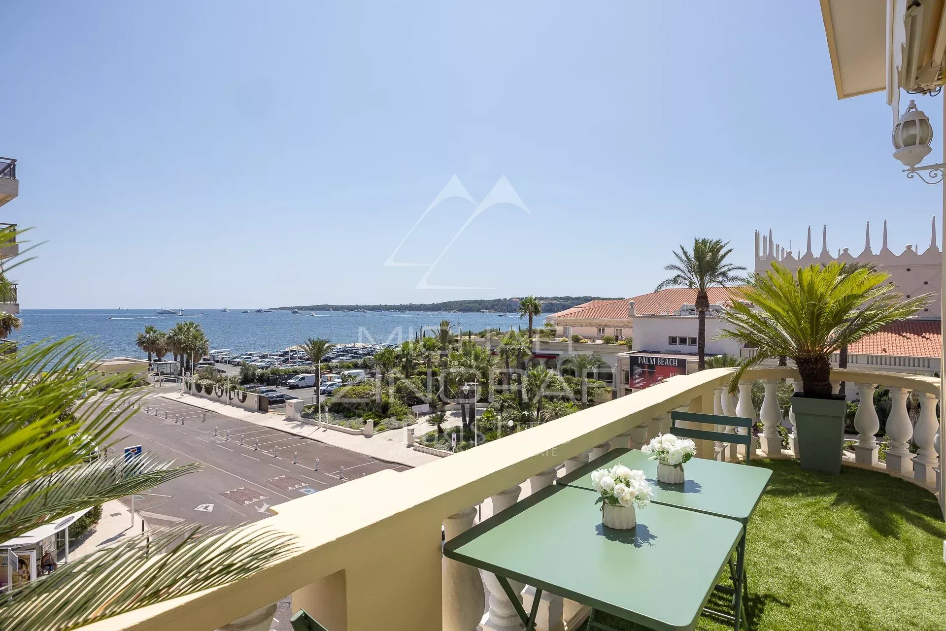 Terrasse d'un appartement à Cannes avec vue sur la mer et les îles, ensoleillée et décorée de plantes.