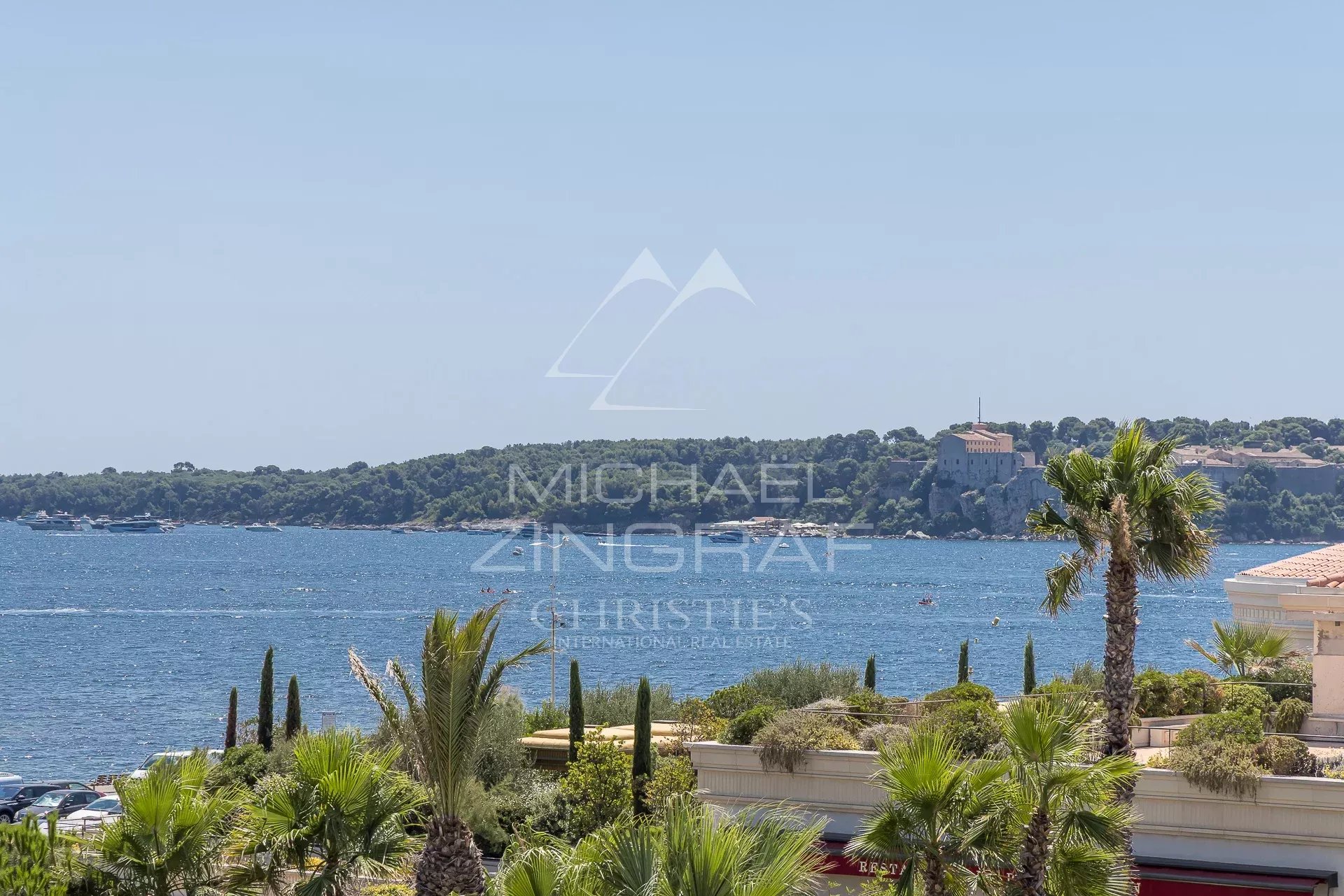 Vue sur la mer depuis une terrasse d'appartement à Cannes, entourée de palmiers.
