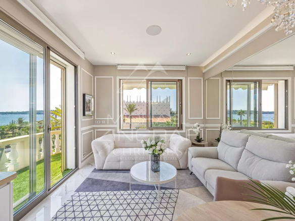 Intérieur d'un appartement à Cannes avec vue sur la mer, salon lumineux et terrasse.