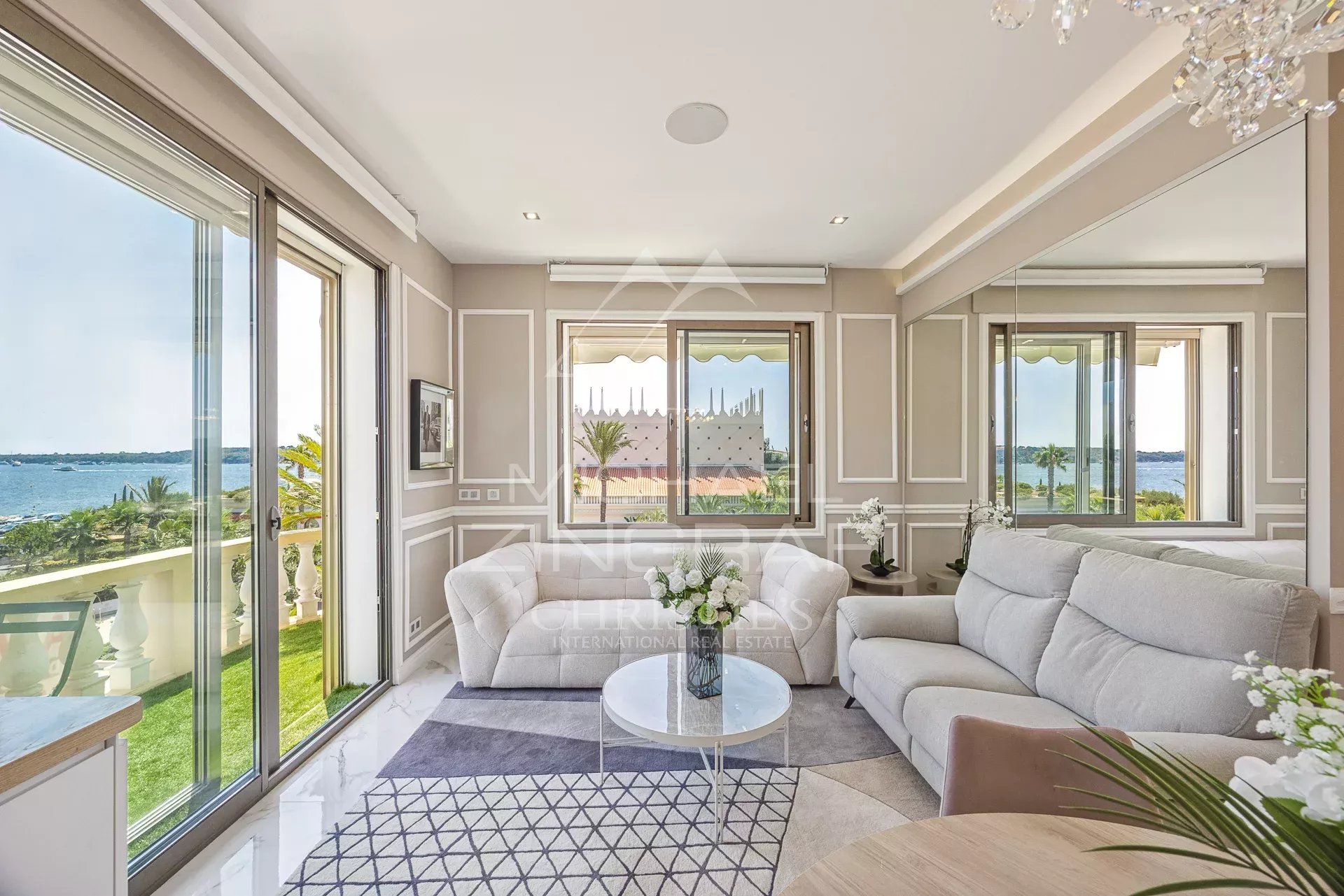 Intérieur d'un appartement à Cannes avec vue sur la mer, salon lumineux et terrasse.