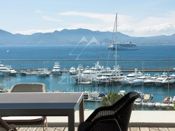 Panoramic view of the sea and the port of Cannes from a penthouse with outdoor furniture.