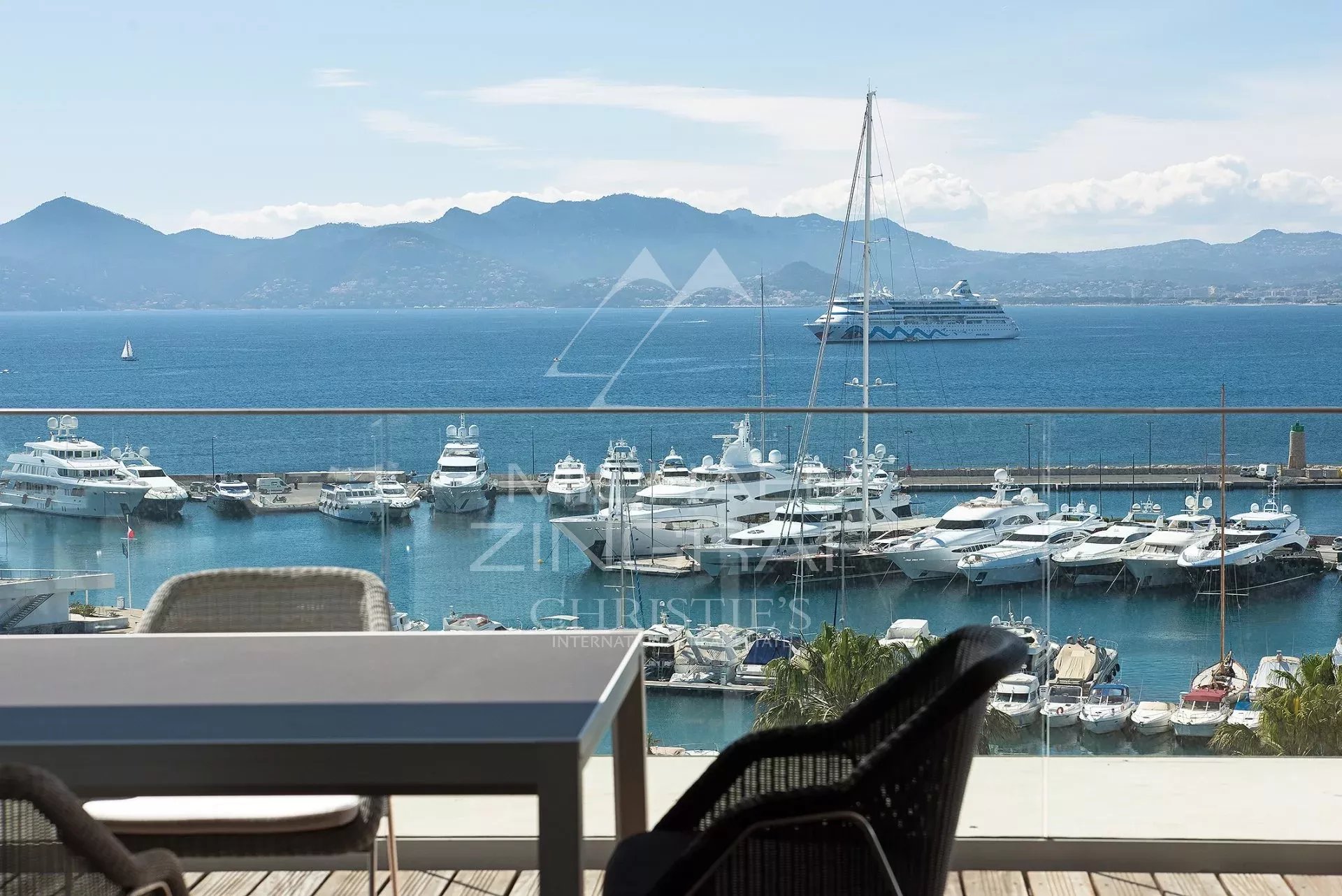Panoramic view of the sea and the port of Cannes from a penthouse with outdoor furniture.
