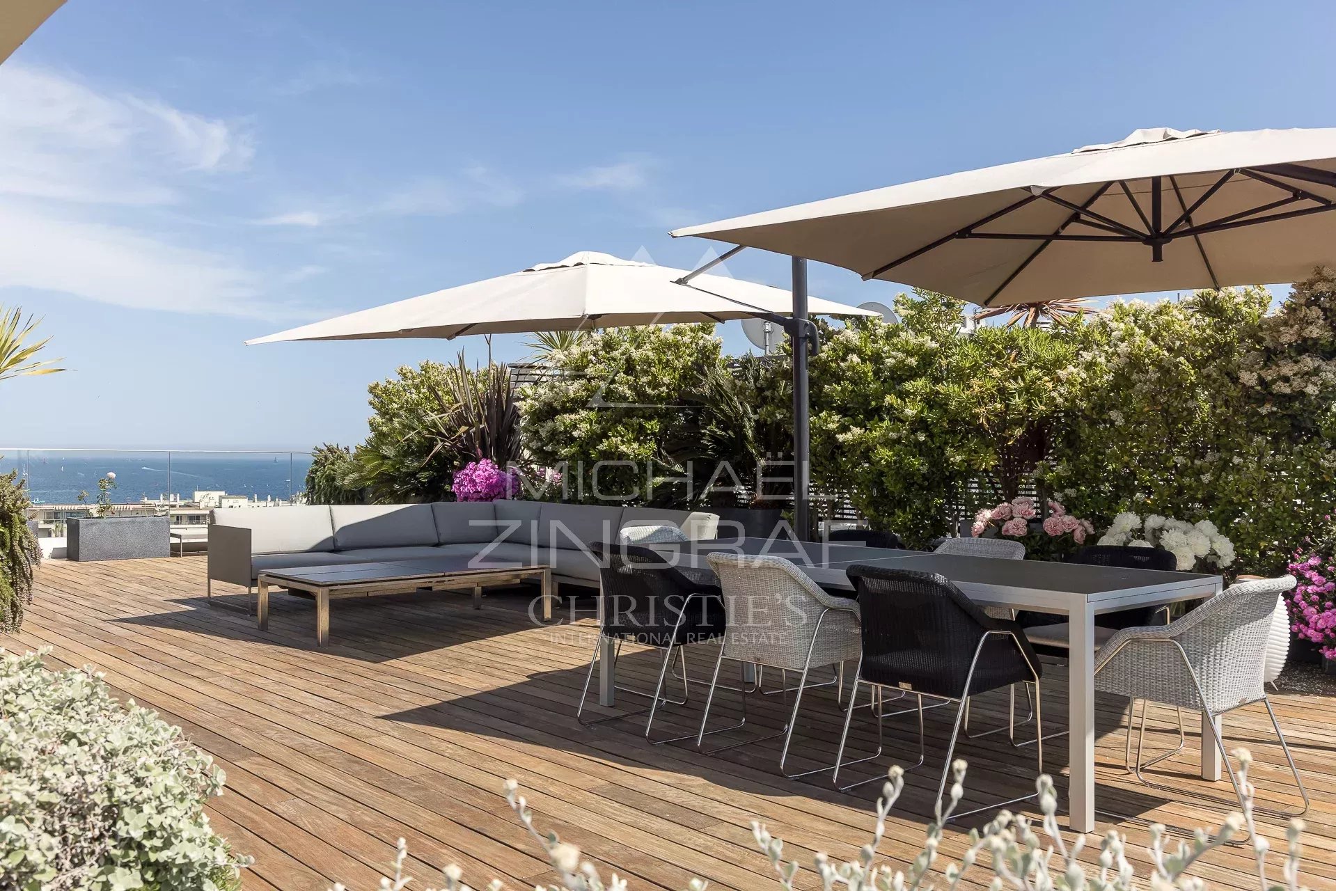 Terrace of a penthouse in Cannes with sea view, modern furniture and parasols.