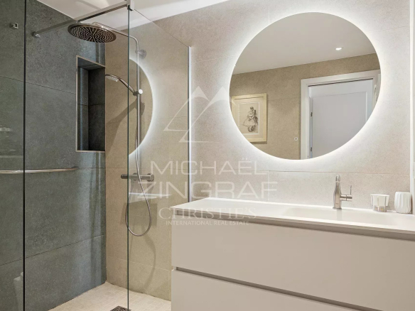 Salle de bain moderne avec douche à l'italienne et meuble vasque, éclairage doux.