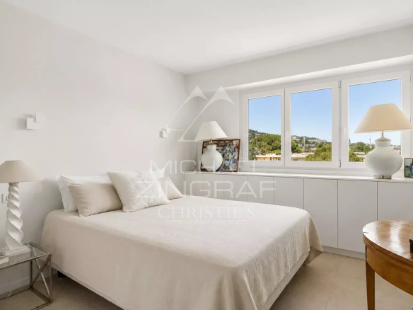 Chambre d'un appartement élégant à Cannes, avec lit et fenêtre lumineuse.