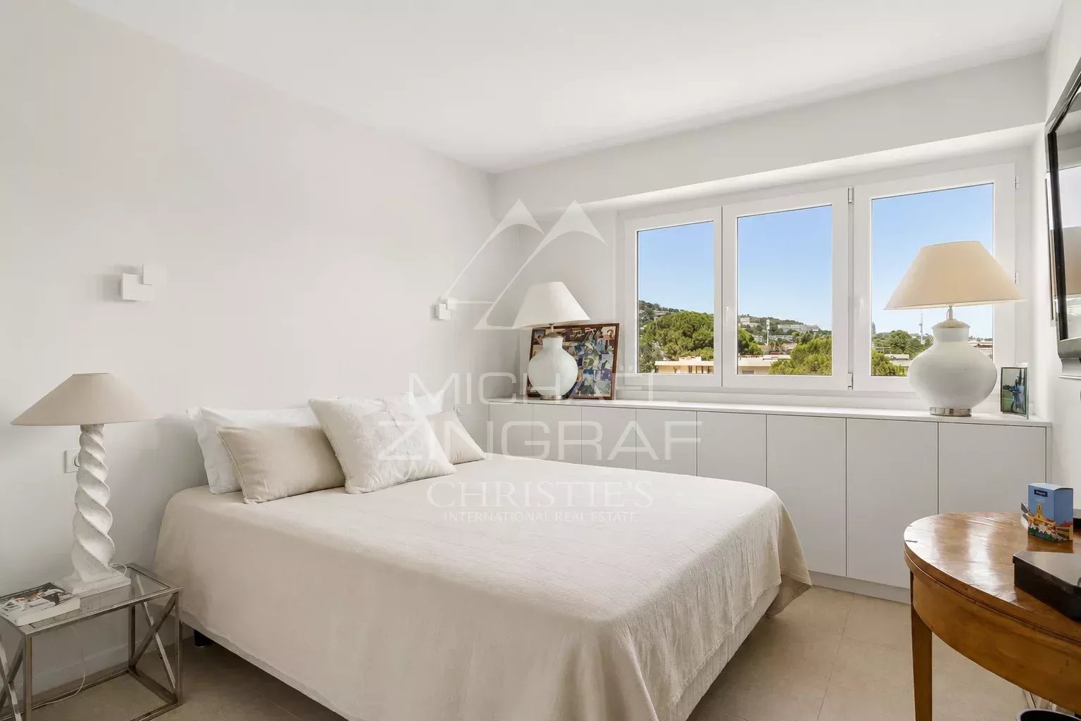 Chambre d'un appartement élégant à Cannes, avec lit et fenêtre lumineuse.