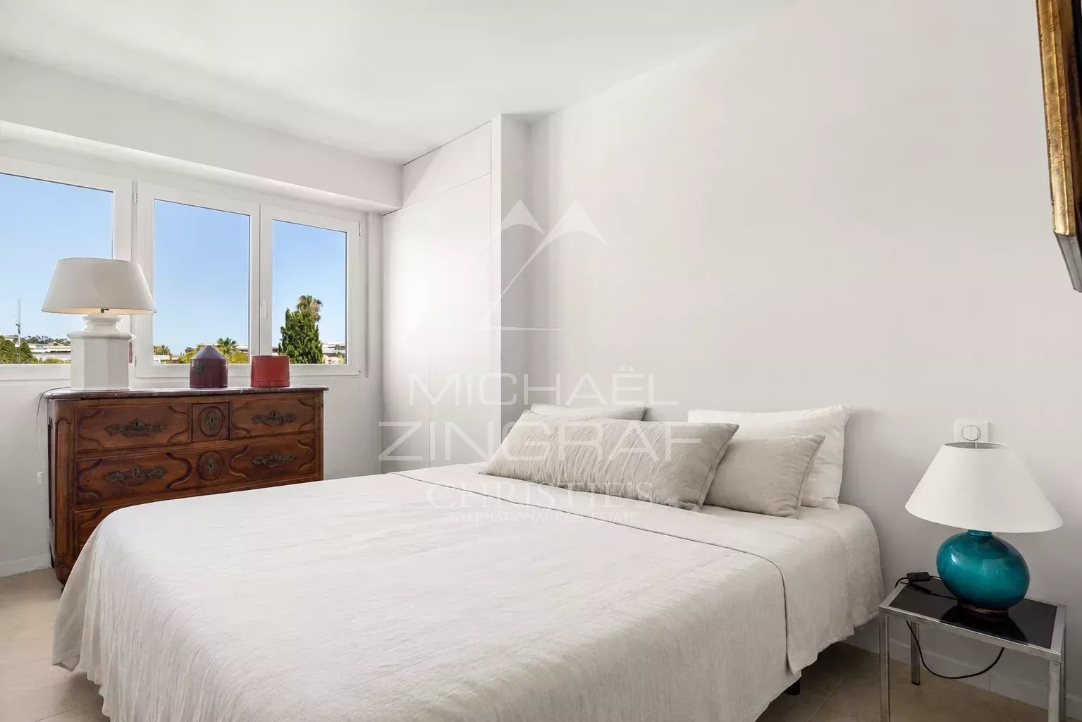 Chambre d'un appartement moderne à Cannes avec lit double et fenêtres lumineuses.