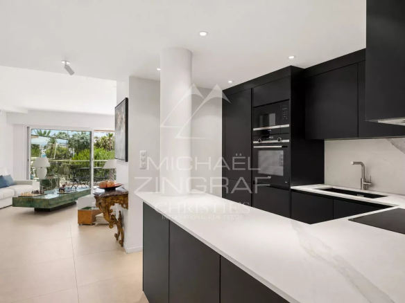 Cuisine moderne d'un appartement à Cannes avec un séjour lumineux en arrière-plan.