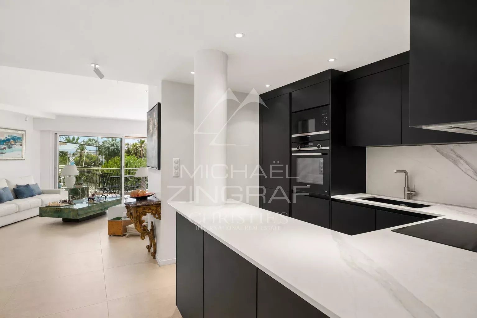 Cuisine moderne d'un appartement à Cannes avec un séjour lumineux en arrière-plan.