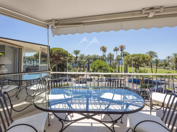 Terrasse d'un appartement à Cannes avec vue sur la Croisette et des palmiers.