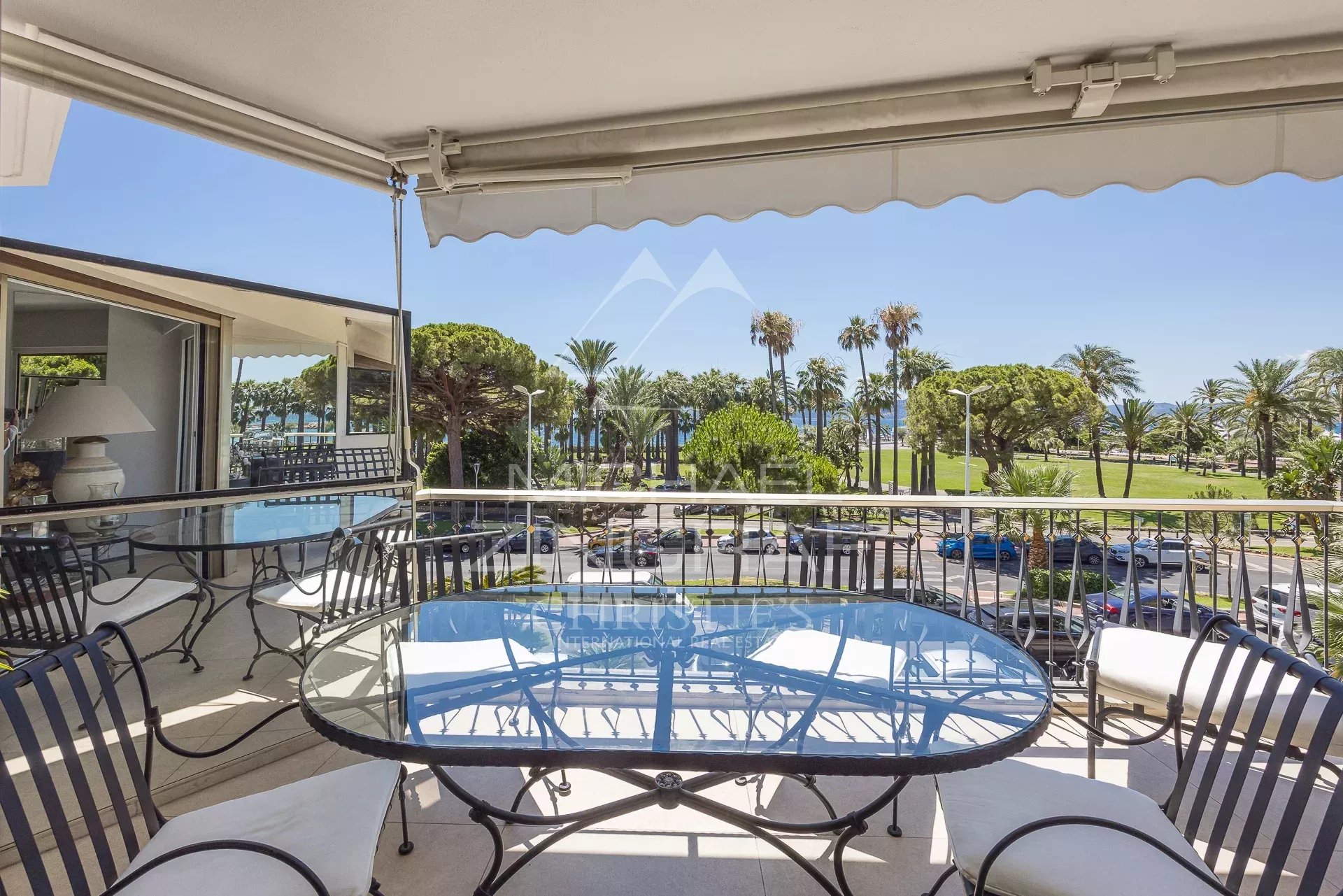 Terrasse d'un appartement à Cannes avec vue sur la Croisette et des palmiers.
