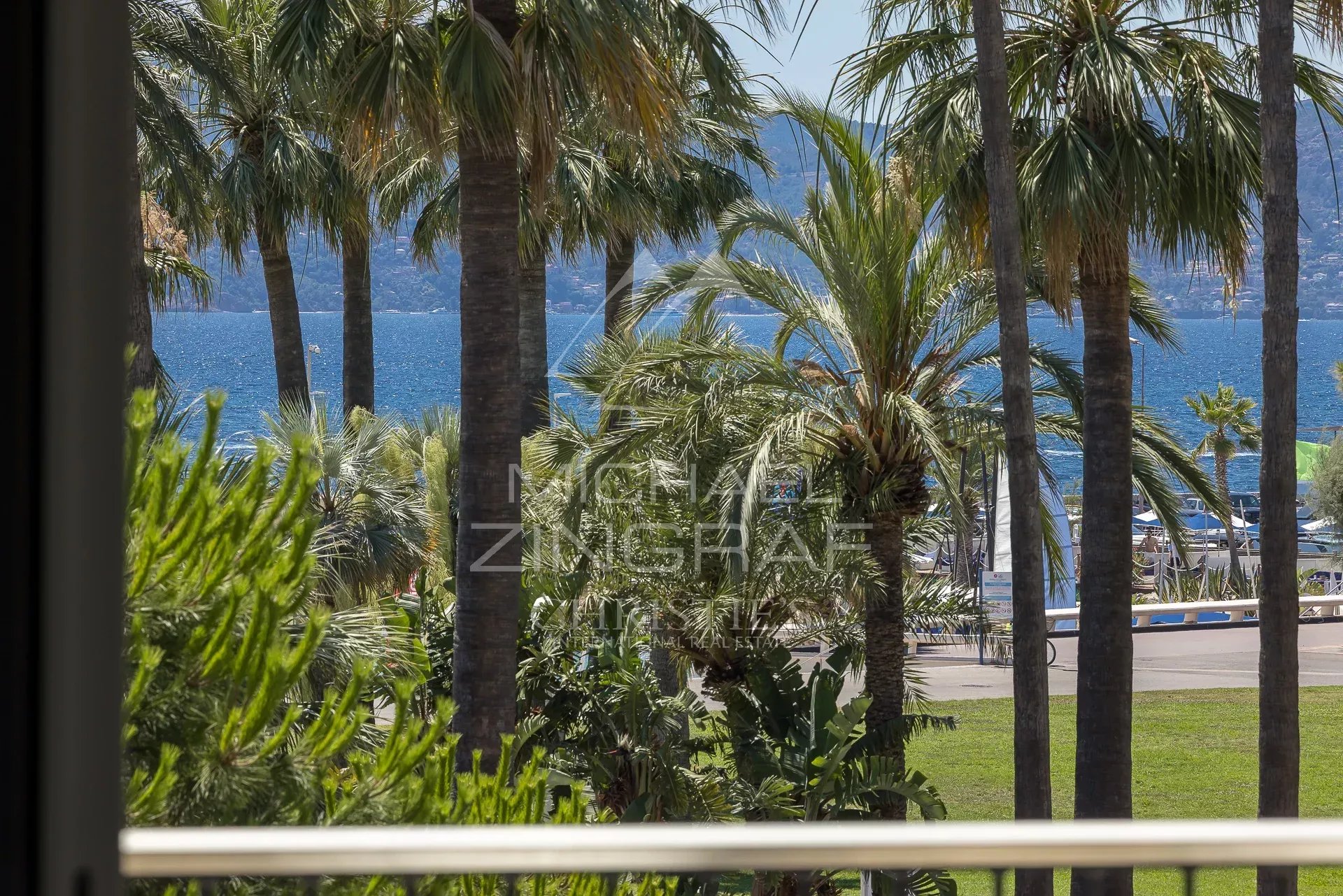 Vue sur la mer et des palmiers depuis une terrasse à Cannes.