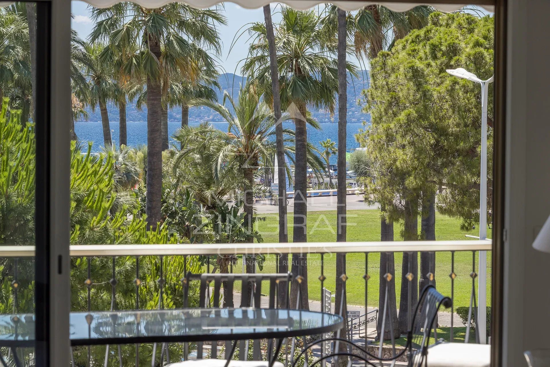 Vue depuis une terrasse avec des palmiers et la mer en arrière-plan à Cannes.