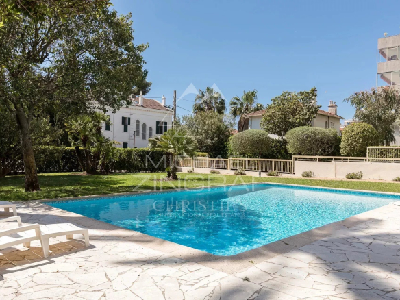 Swimming pool of a residence in Cannes Palm Beach, surrounded by trees and lawn.