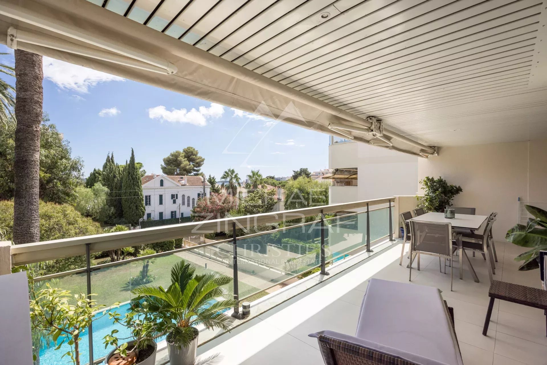Terrace of an apartment in Cannes overlooking the swimming pool and green spaces.