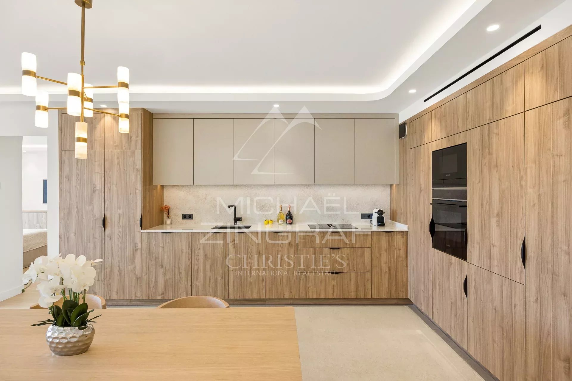 Cuisine d’un appartement à Cannes Cuisine moderne et élégante d'un appartement à Cannes, avec mobilier en bois et table à manger.
