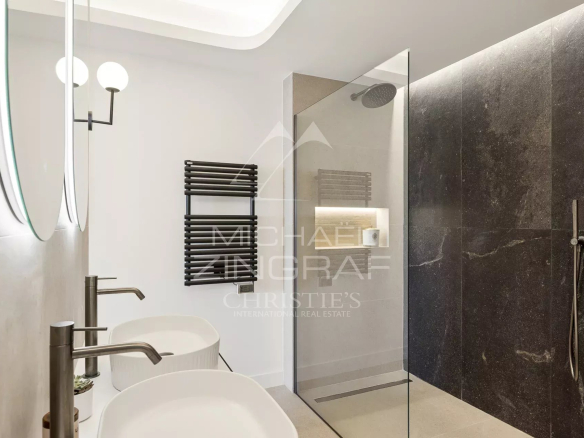 Salle de bain moderne avec douche en verre et vasques doubles dans un appartement rénové.
