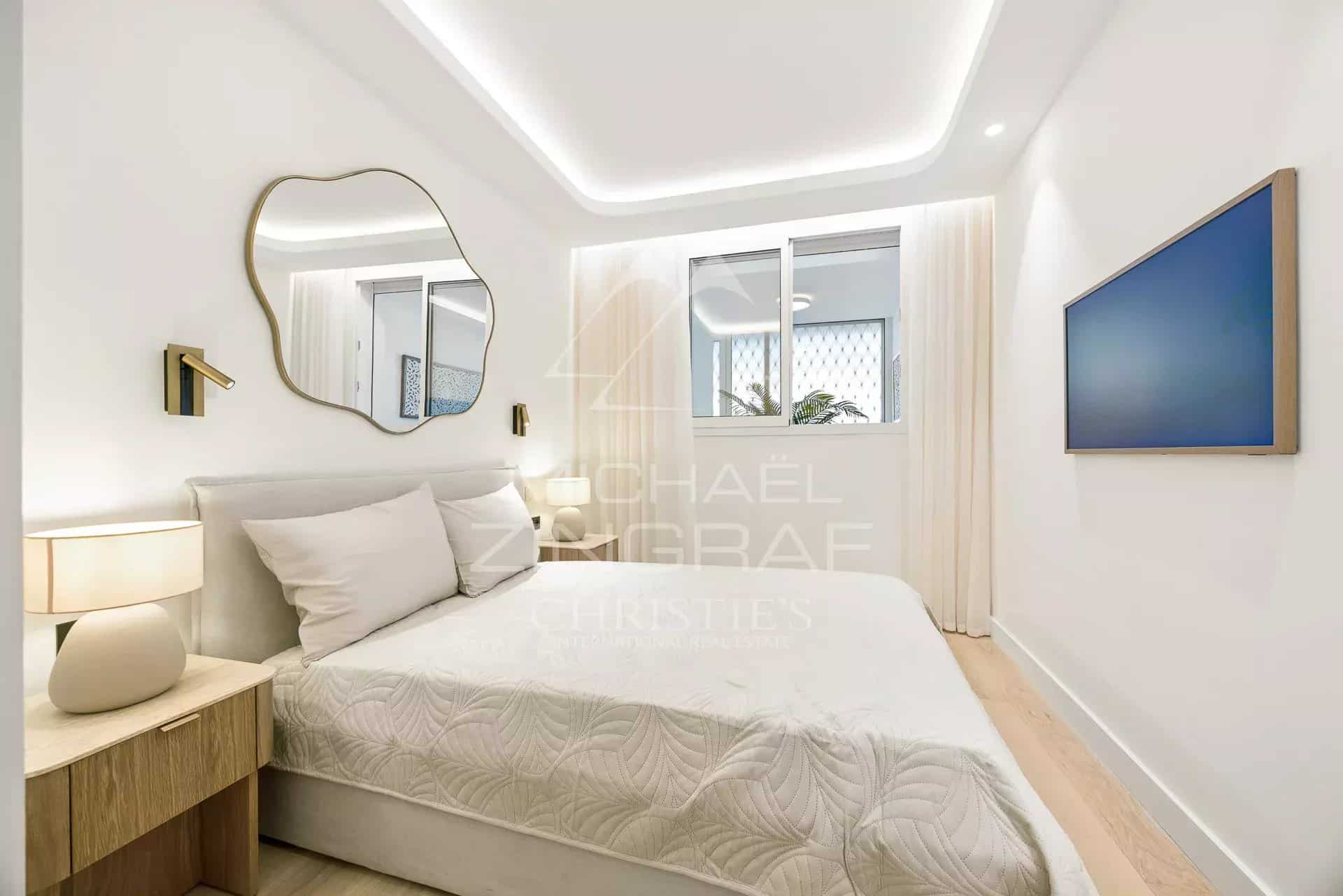 Chambre d’appartement à Palm Beach Chambre d'un appartement moderne avec lit, miroir et télévision murale.