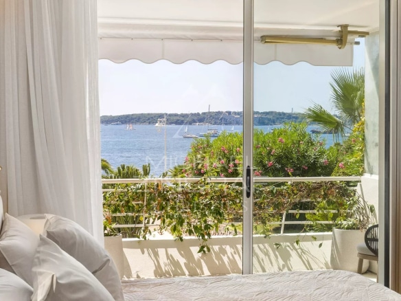 Vue depuis une chambre d'un appartement à Palm Beach, avec mer et végétation en arrière-plan.
