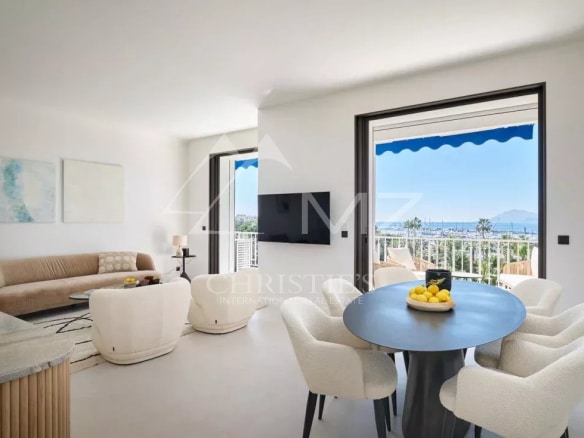 Intérieur d'un appartement rénové à Cannes avec vue sur la mer, salon lumineux et salle à manger.