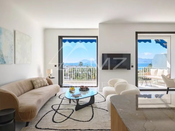 Intérieur d'un appartement rénové à Cannes avec vue sur la mer, salon lumineux et terrasse.