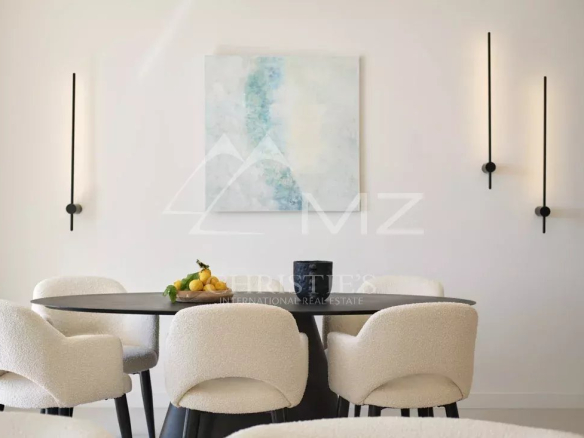 Salle à manger moderne avec table ronde et chaises blanches, décorée d'une œuvre d'art murale.