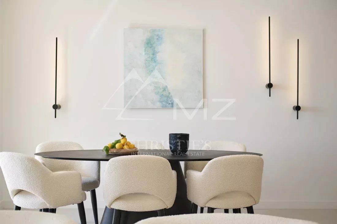 Salle à manger moderne à Cannes Salle à manger moderne avec table ronde et chaises blanches, décorée d'une œuvre d'art murale.