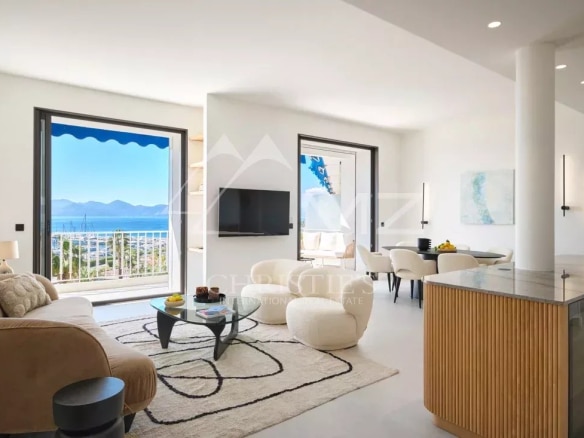 Intérieur d'un appartement rénové à Cannes avec vue sur la mer, salon lumineux et cuisine moderne.