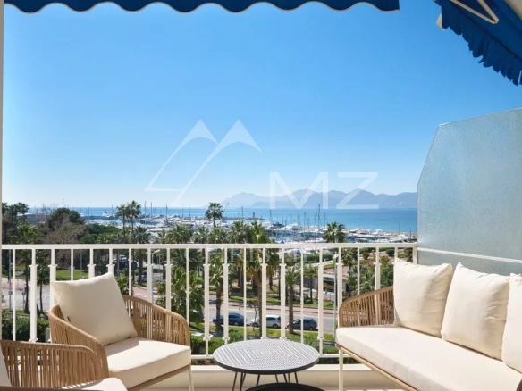 Terrasse d'un appartement rénové à Cannes avec vue sur la mer et le port.
