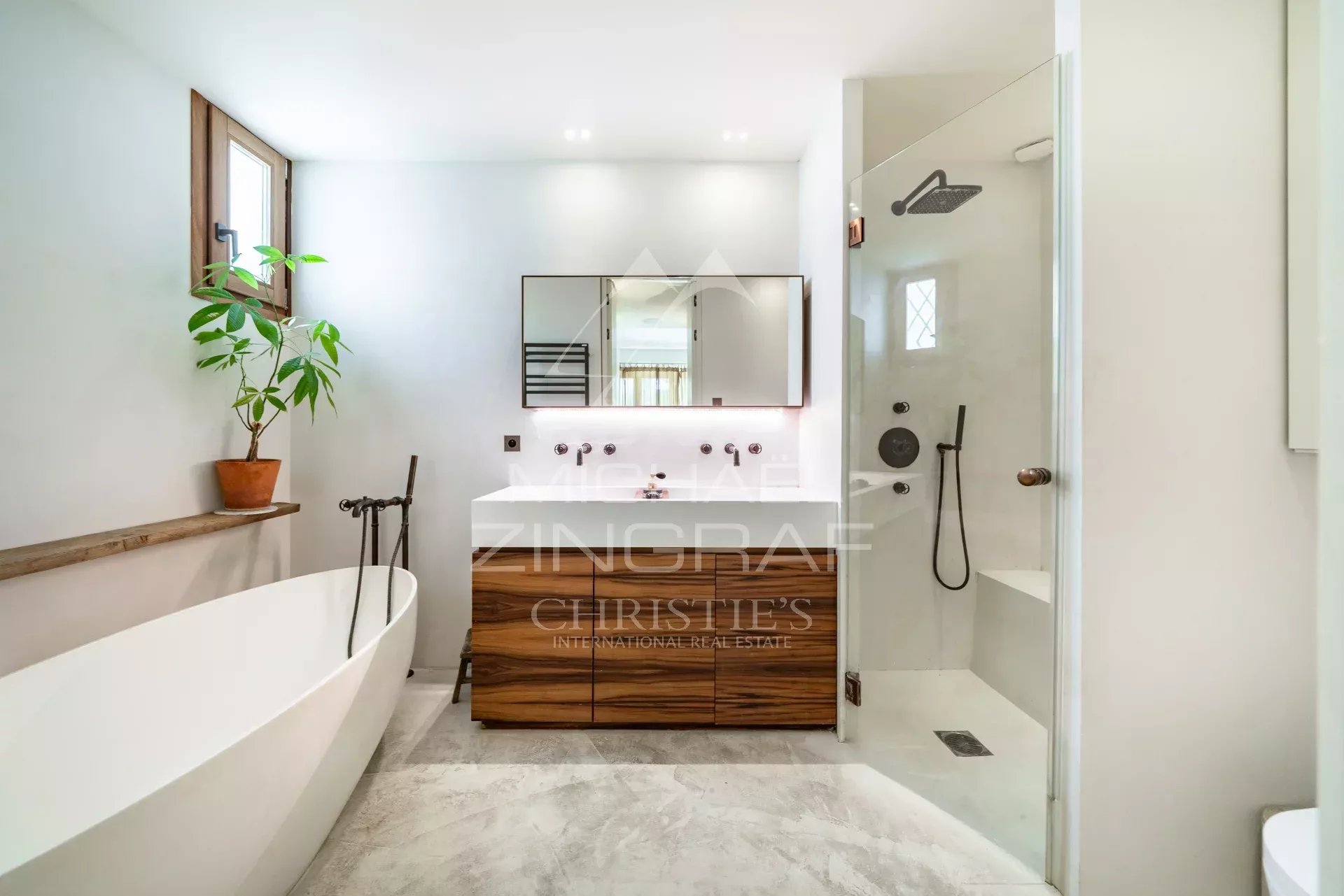 Salle de bain élégante Salle de bain moderne avec baignoire et douche, plantes vertes, et meuble en bois.