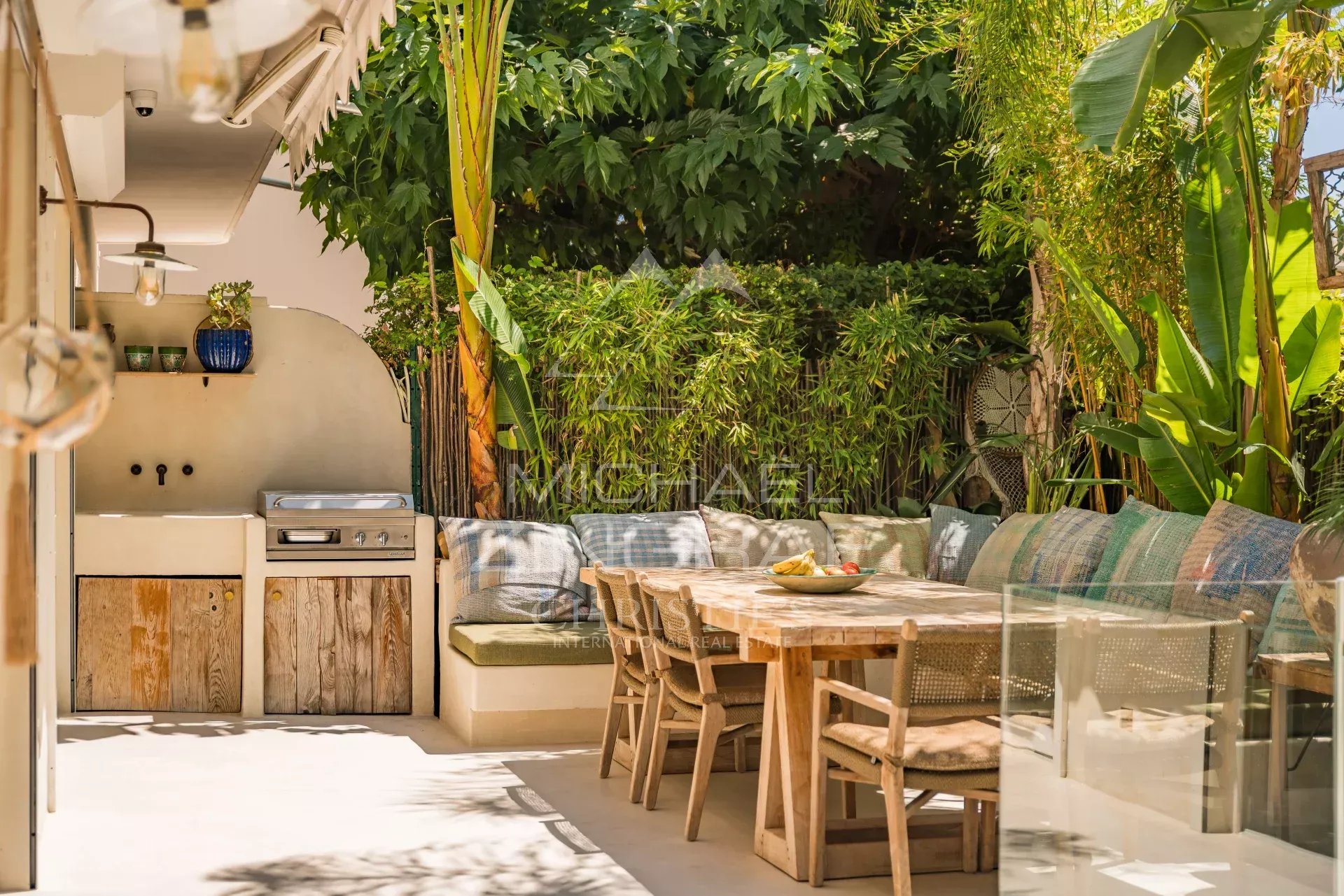 Terrasse avec piscine privative à Cannes Terrasse avec mobilier en bois et cuisine extérieure, entourée de verdure, dans un appartement à Cannes.