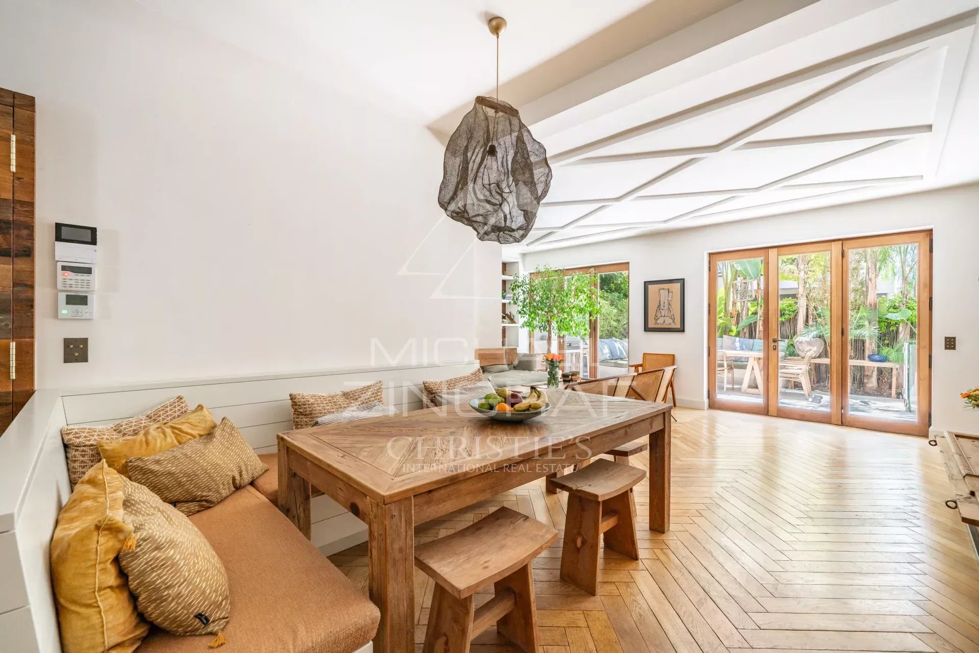 Appartement élégant à Cannes Intérieur d'un appartement à Cannes avec salle à manger en bois et accès à une terrasse tropicale.