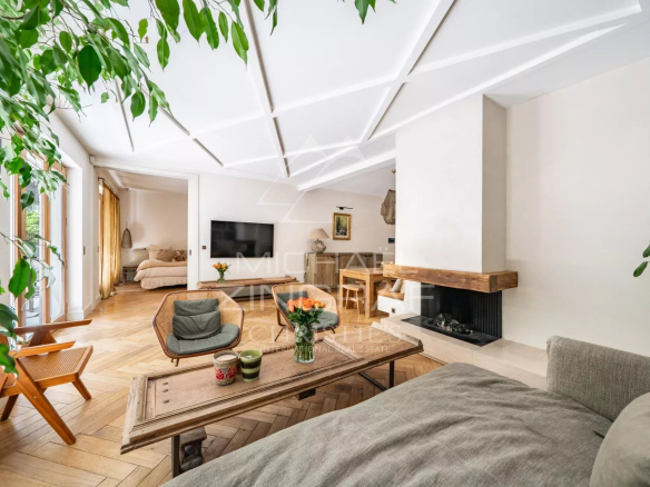 Intérieur d'un appartement élégant avec salon lumineux, cheminée et terrasse tropicale.