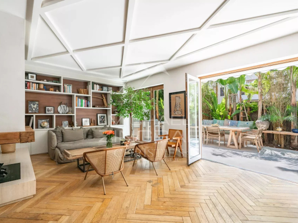 Intérieur d'un appartement en rez-de-jardin à Cannes avec salon lumineux et accès à une terrasse tropicale.