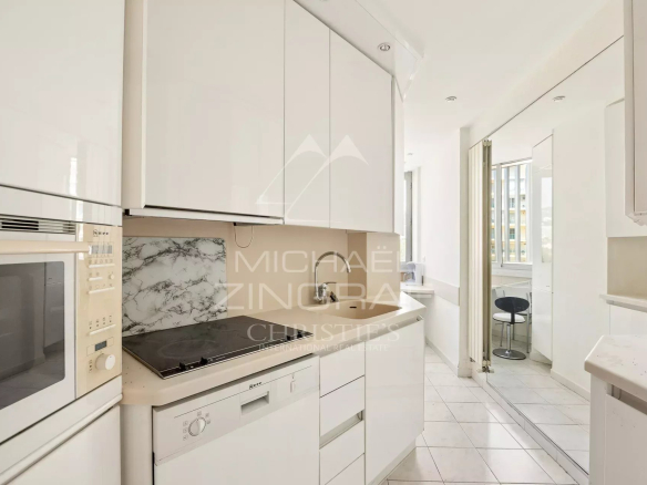 Cuisine moderne et lumineuse d'un appartement à Cannes, avec éléments en blanc et coin repas.