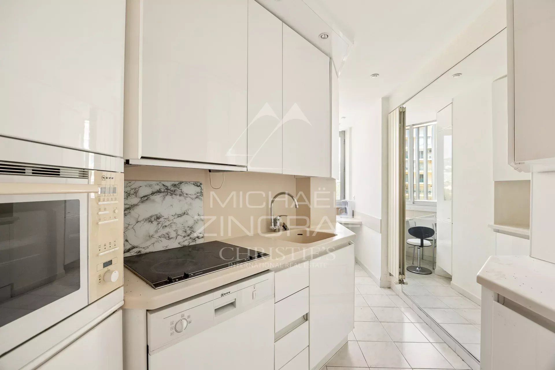 Cuisine d’un appartement à Cannes Cuisine moderne et lumineuse d'un appartement à Cannes, avec éléments en blanc et coin repas.